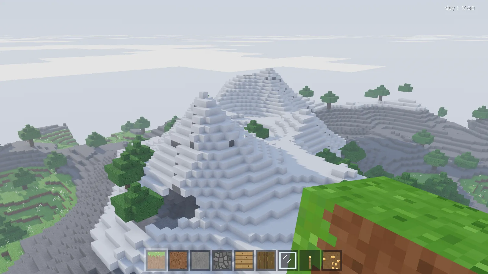 Snow-capped voxel mountains rising above pine trees into haze